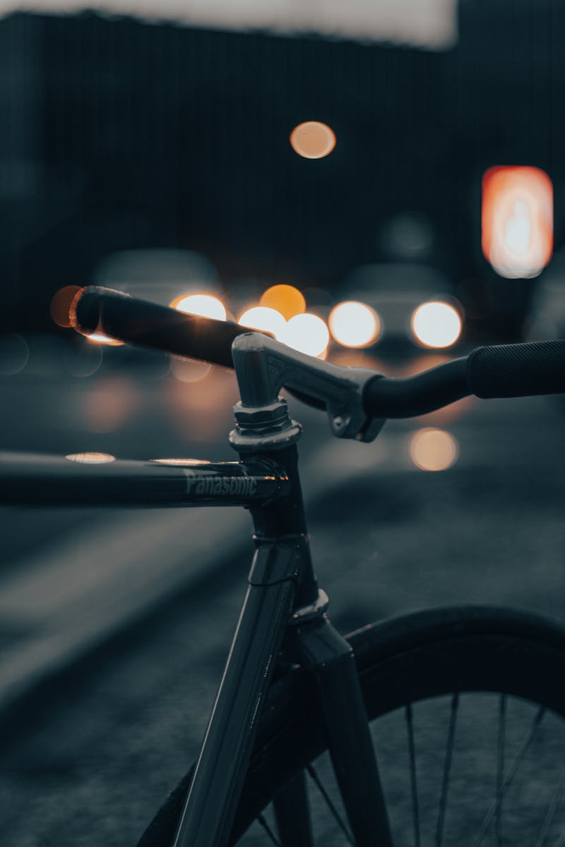 Artistic shot of bicycle handlebars with a blurred night cityscape and bokeh lights.