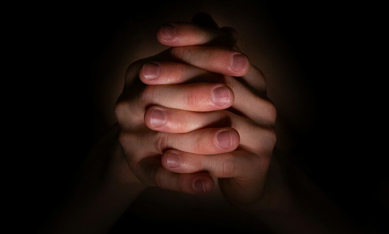 a person holding their hands together in the dark